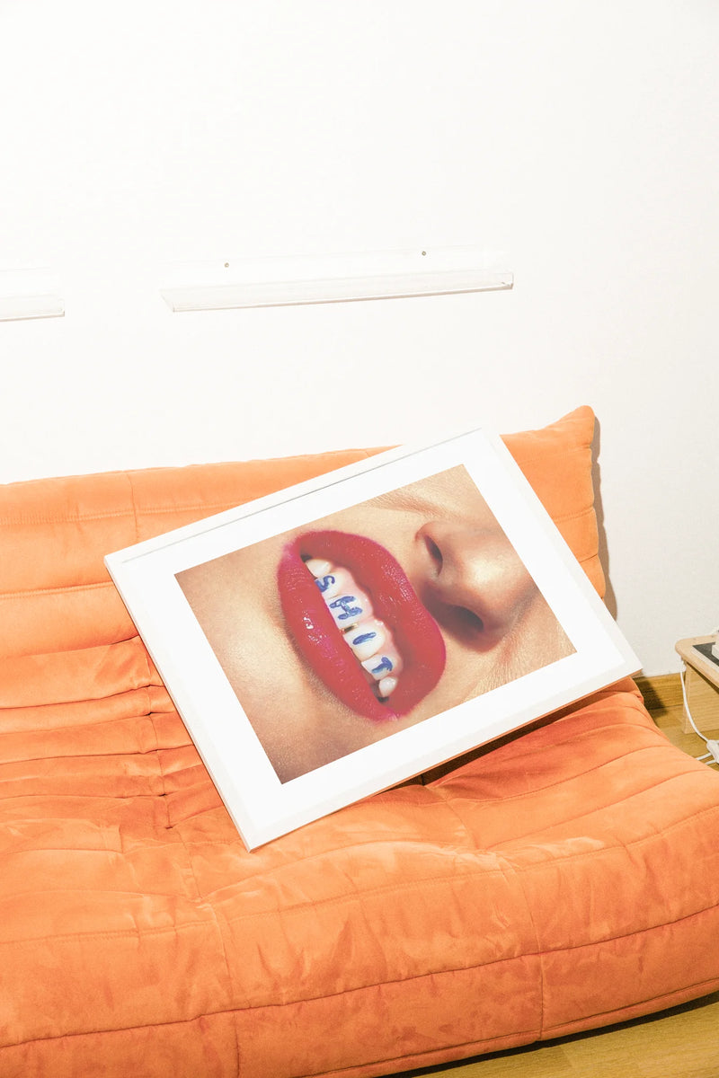 Des lèvres rouges vives sur des dents d'un blanc éclatant encadrent des lettres bleues audacieuses épelant SHIT. Un gros plan serré et réaliste capture un portrait audacieux à l'ambiance confrontante.. bold, portrait, red, typographic, white