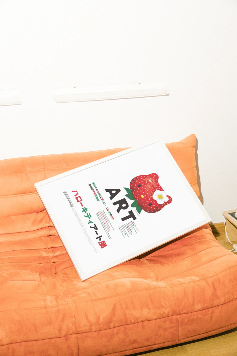 Une illustration numérique d'une tête de Hello Kitty espiègle en forme de fraise avec une fleur blanche, un texte 'ART' audacieux et des détails d'événement.. green, illustration, playful, red, vibrant, white