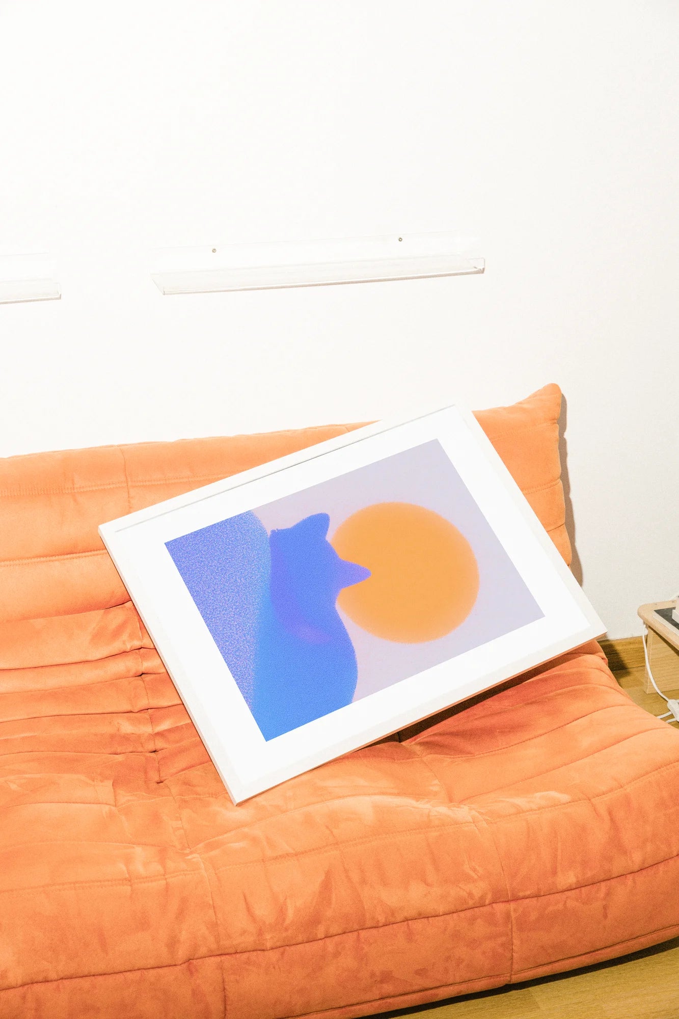Une illustration numérique minimaliste présente une silhouette de chat bleu fantomatique sur un fond bleu texturé, baignée de lumière par un soleil orange éclatant.. blue, digital, minimalist, orange, serene