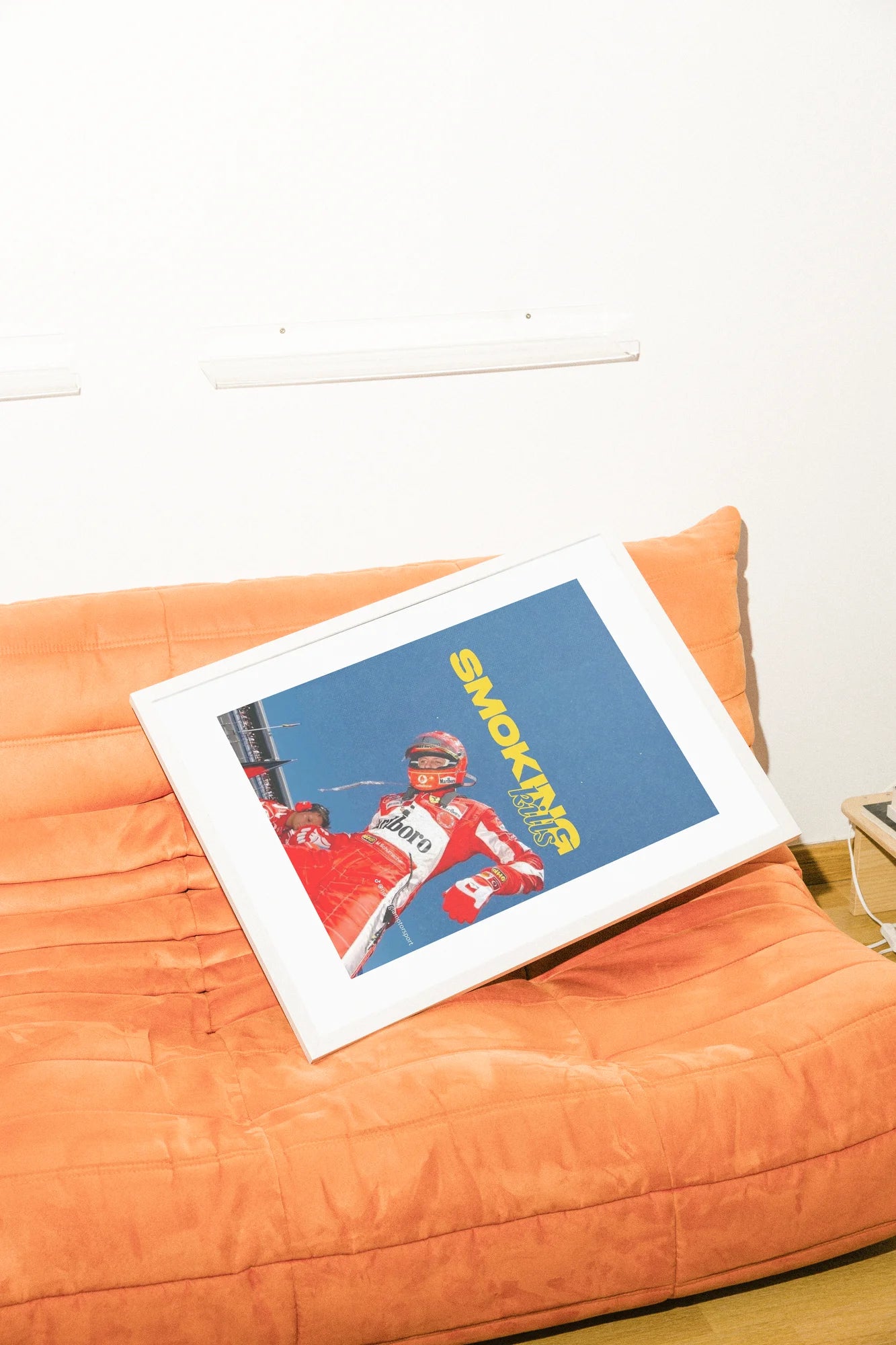 Une photo audacieuse capture un pilote de Formule 1 en rouge éclatant, sur une piste bleue austère avec un texte jaune provocateur défiant les habitudes modernes.. blue, bold, illustration, red, typographic, vibrant, yellow