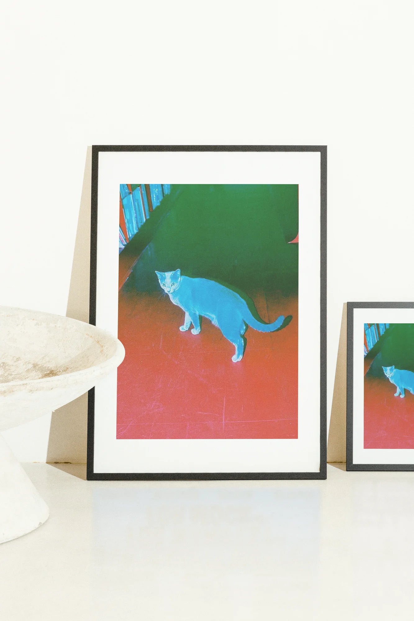 Un chat numérique géométrique se dresse sur un sol rouge vif, sur un fond vert luxuriant. Des teintes saturées audacieuses créent une pièce de galerie ludique et moderne.. animal, blue, geometric, green, red, surreal