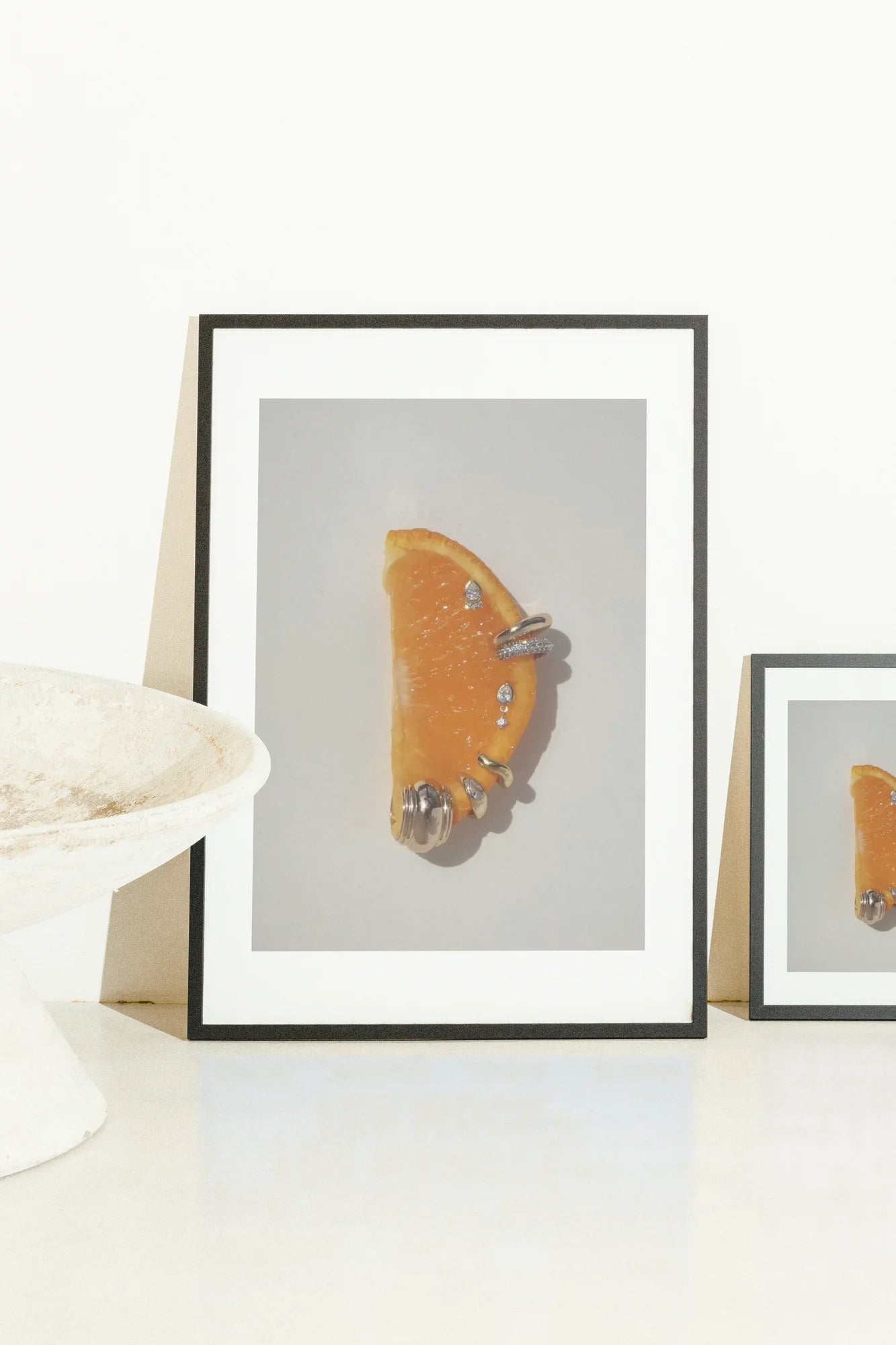 Une tranche d'agrume vibrante couronnée d'anneaux argentés brillants et de détails perlés, créant une fusion ludique de luxe sur une toile blanche éclatante.. minimalist, orange, photographic, vibrant, white